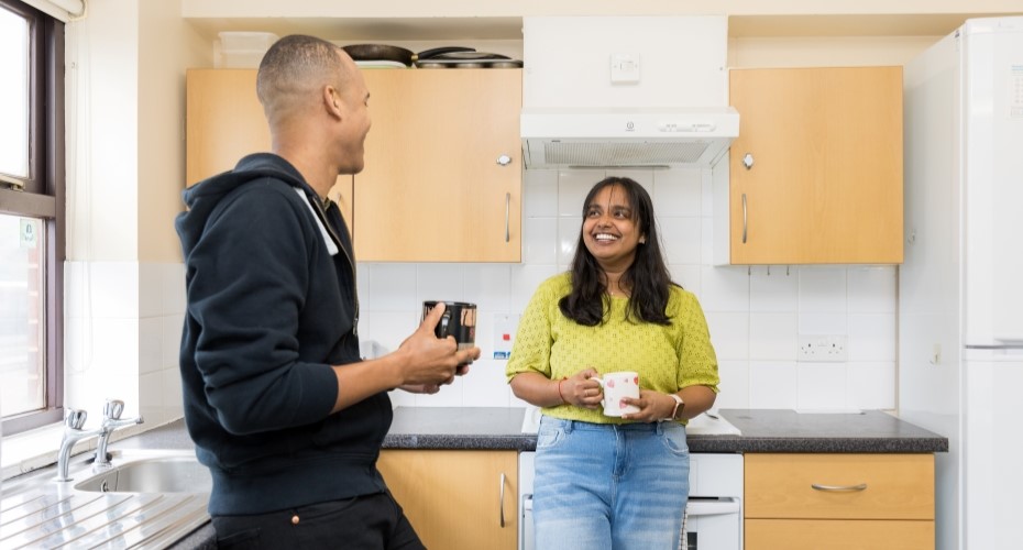 Two smiling students holding mugs in a kitchen in Cook and Llewellyn Mews accommodation