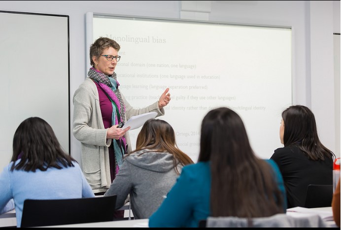 A woman presents to an audience, engaging them with her speech and visual aids in a professional setting.